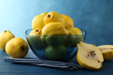 Tasty ripe quinces in bowl on blue wooden table, closeup