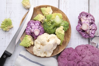 Various cauliflower cabbages on white wooden table, flat lay