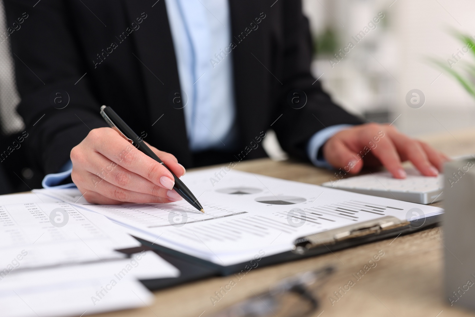 Photo of Secretary doing paperwork at table in office, closeup