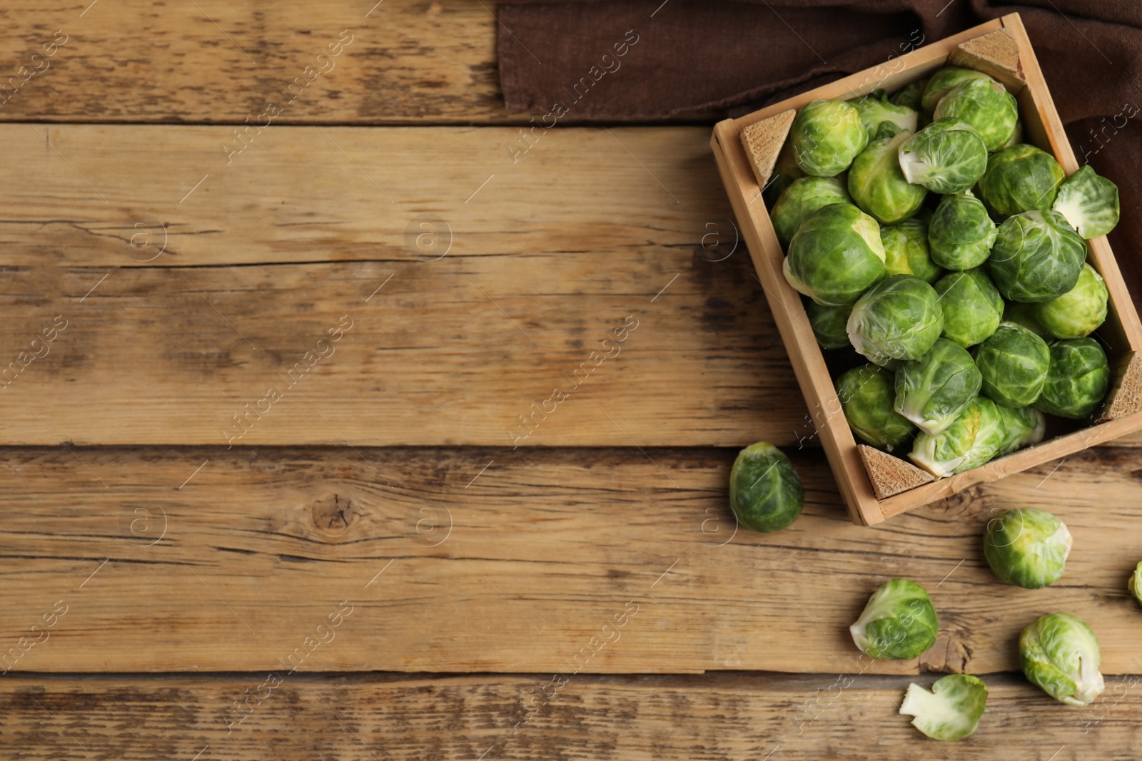 Photo of Fresh Brussels sprouts on wooden table, flat lay. Space for text