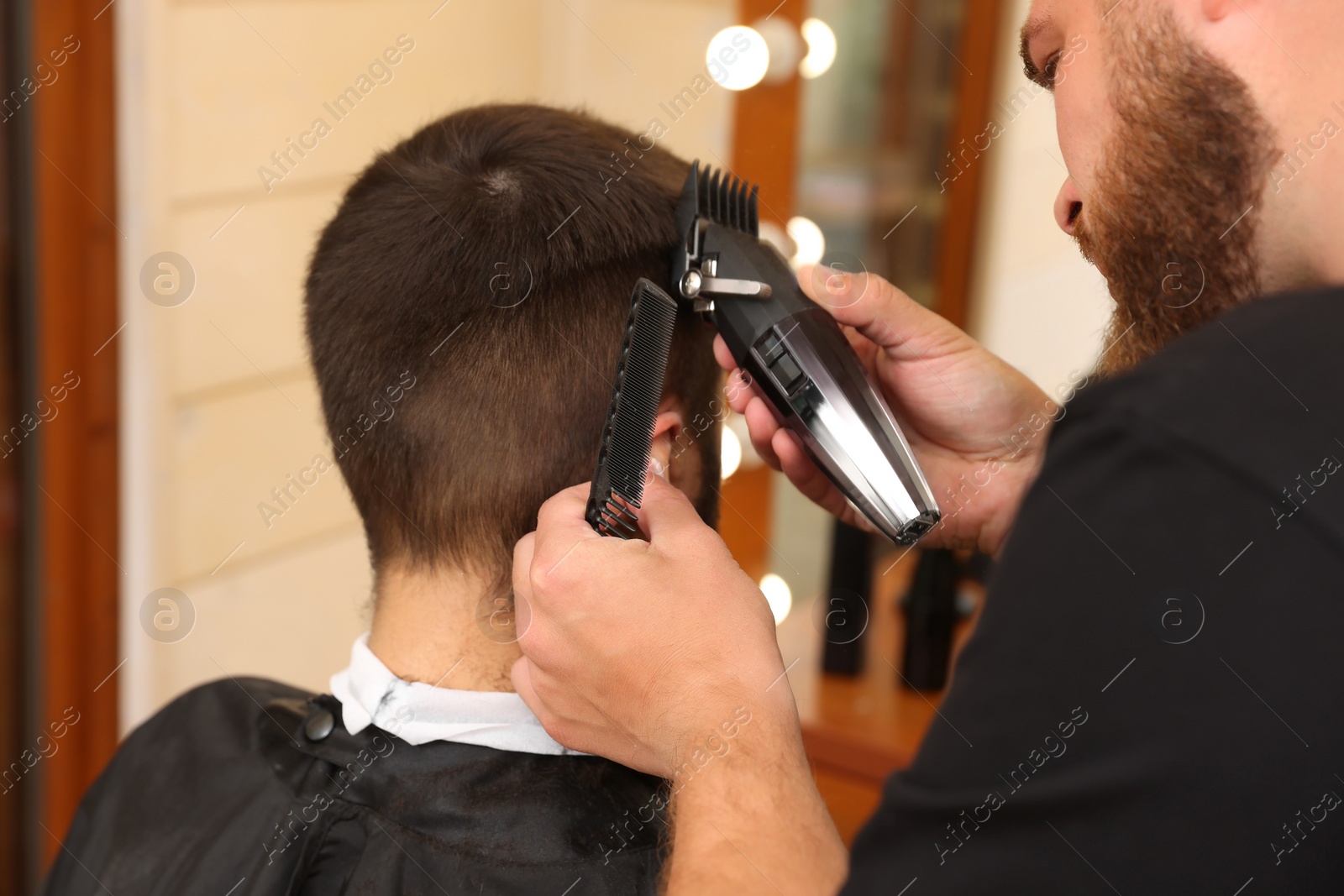 Photo of Professional hairdresser working with client in barbershop, closeup