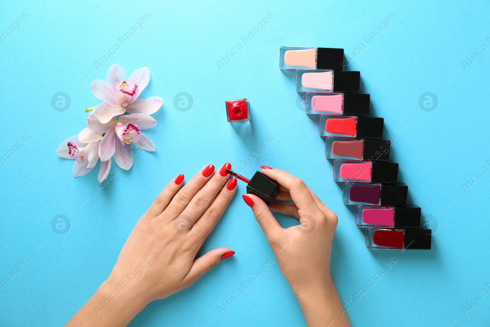 Photo of Woman applying bright nail polish on color background, top view