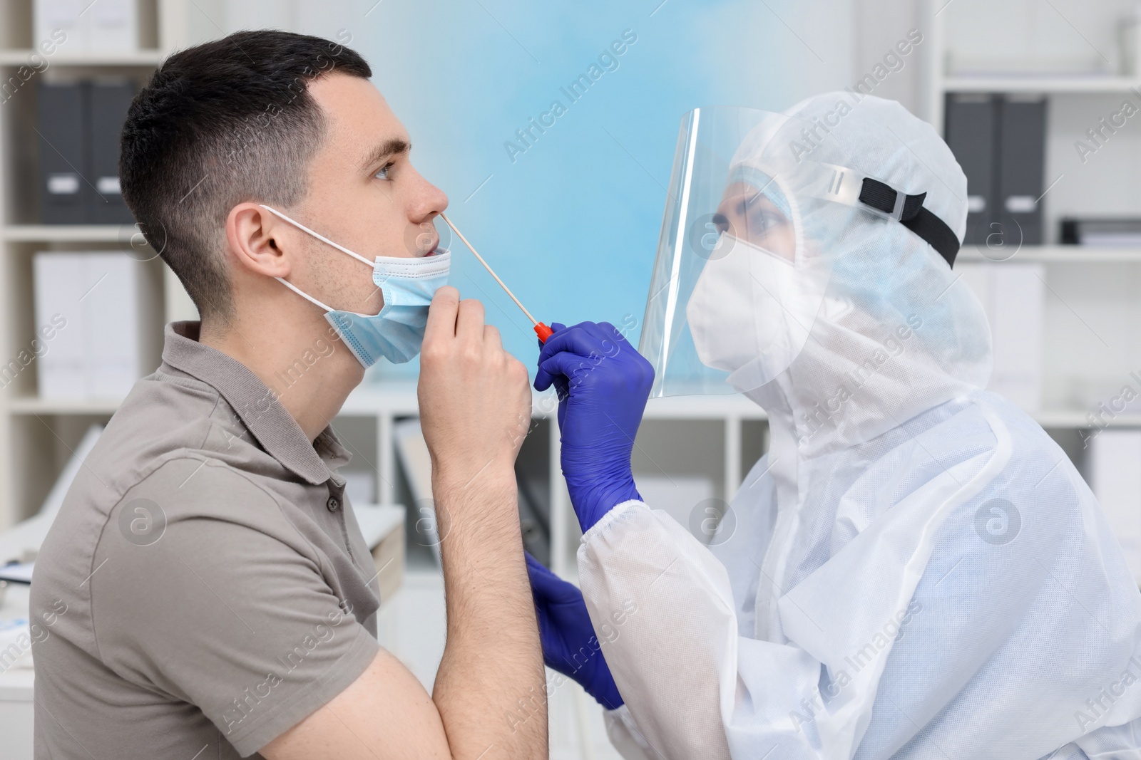 Photo of Laboratory testing. Doctor in uniform taking sample from patient's nose with cotton swab at hospital