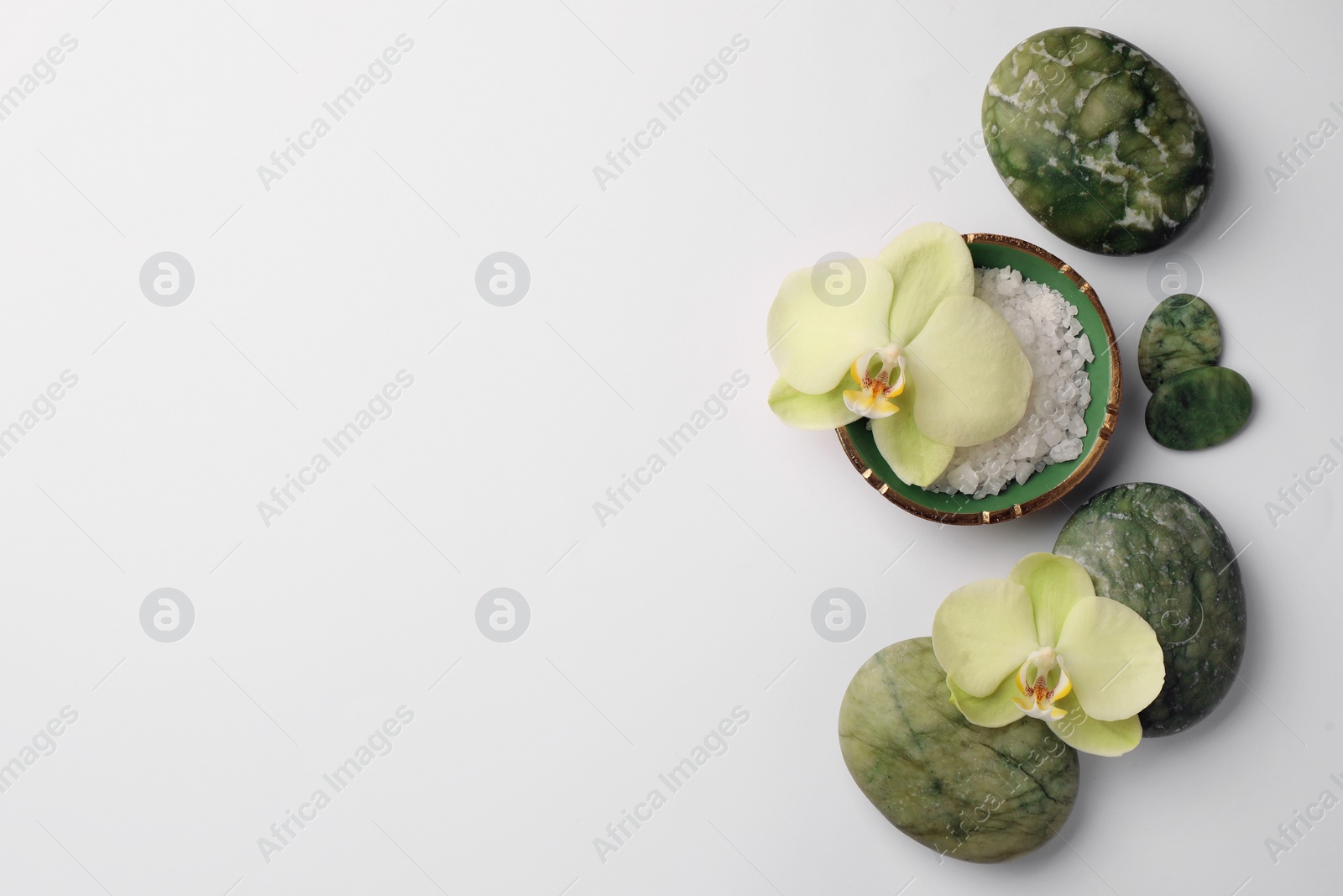 Photo of Flat lay composition with spa stones, salt and beautiful flowers on white table. Space for text