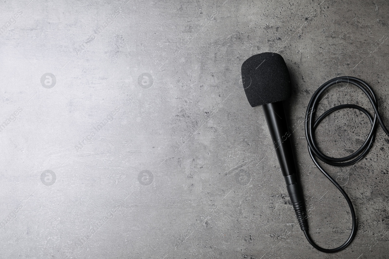 Photo of Modern microphone on grey background, top view with space for text