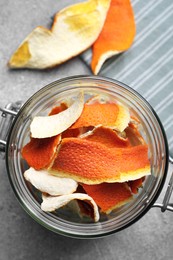 Photo of Glass jar with dry orange peels on light gray table, top view