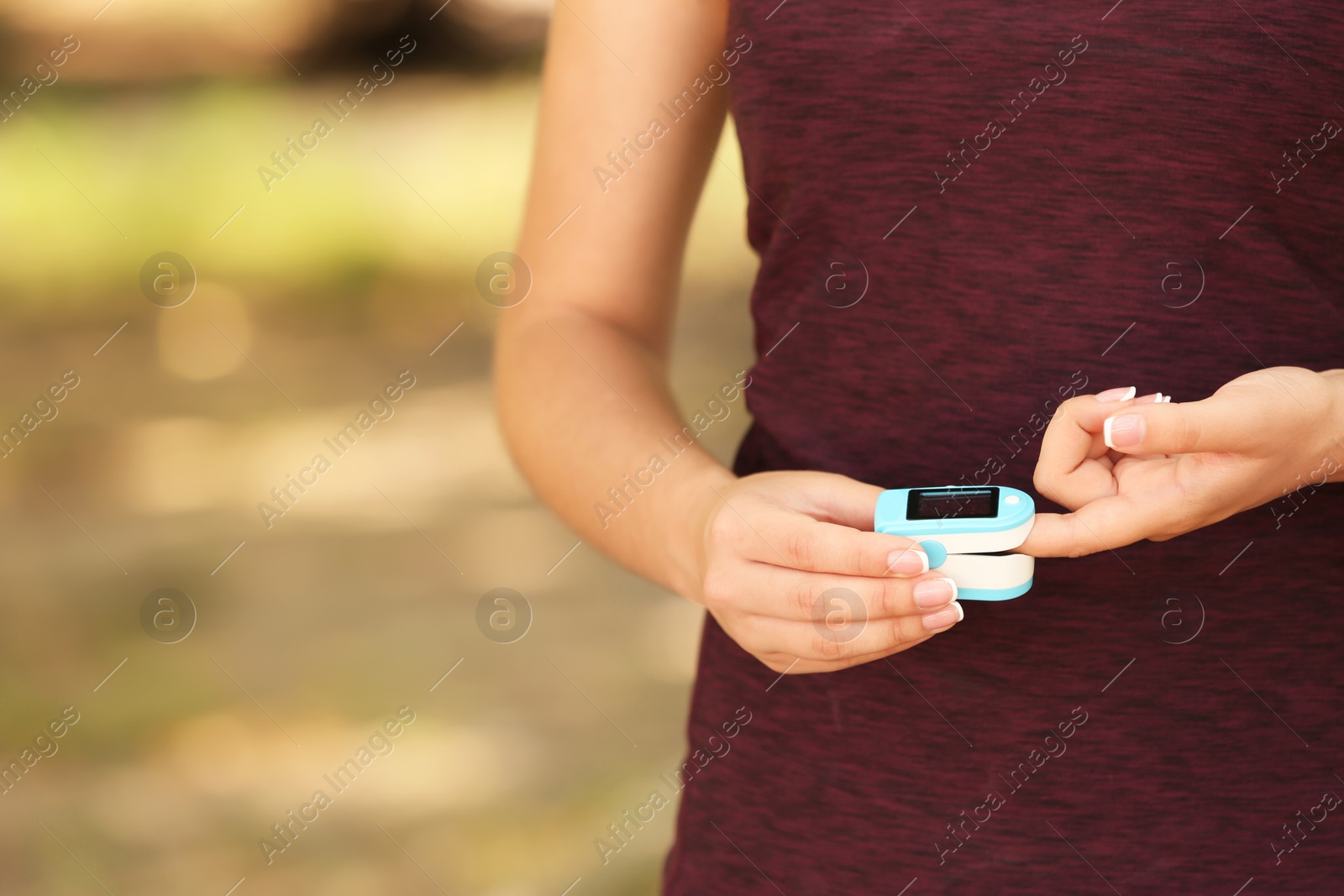 Photo of Young woman checking pulse outdoors on sunny day