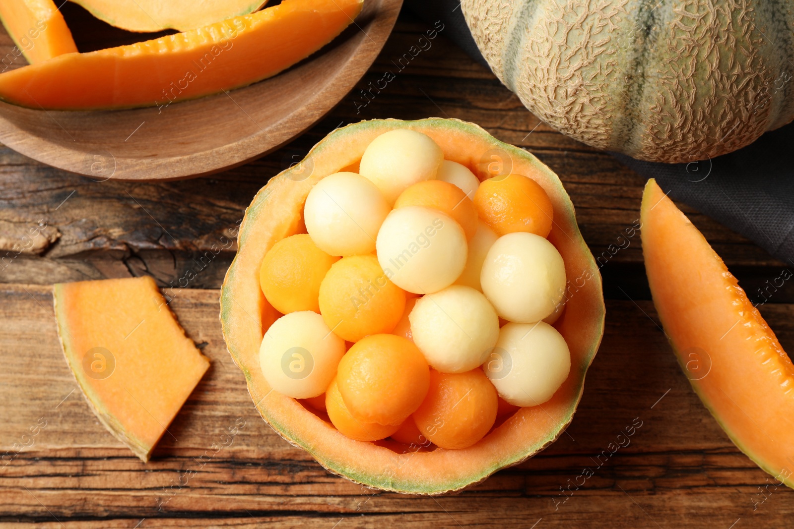 Photo of Different melon balls on wooden table, flat lay