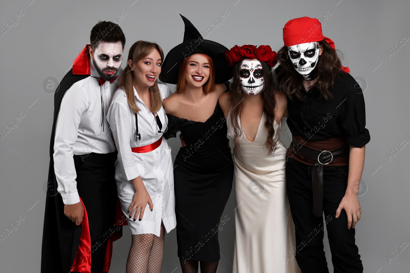 Photo of Group of people in scary costumes on light grey background. Halloween celebration