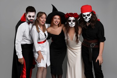 Group of people in scary costumes on light grey background. Halloween celebration