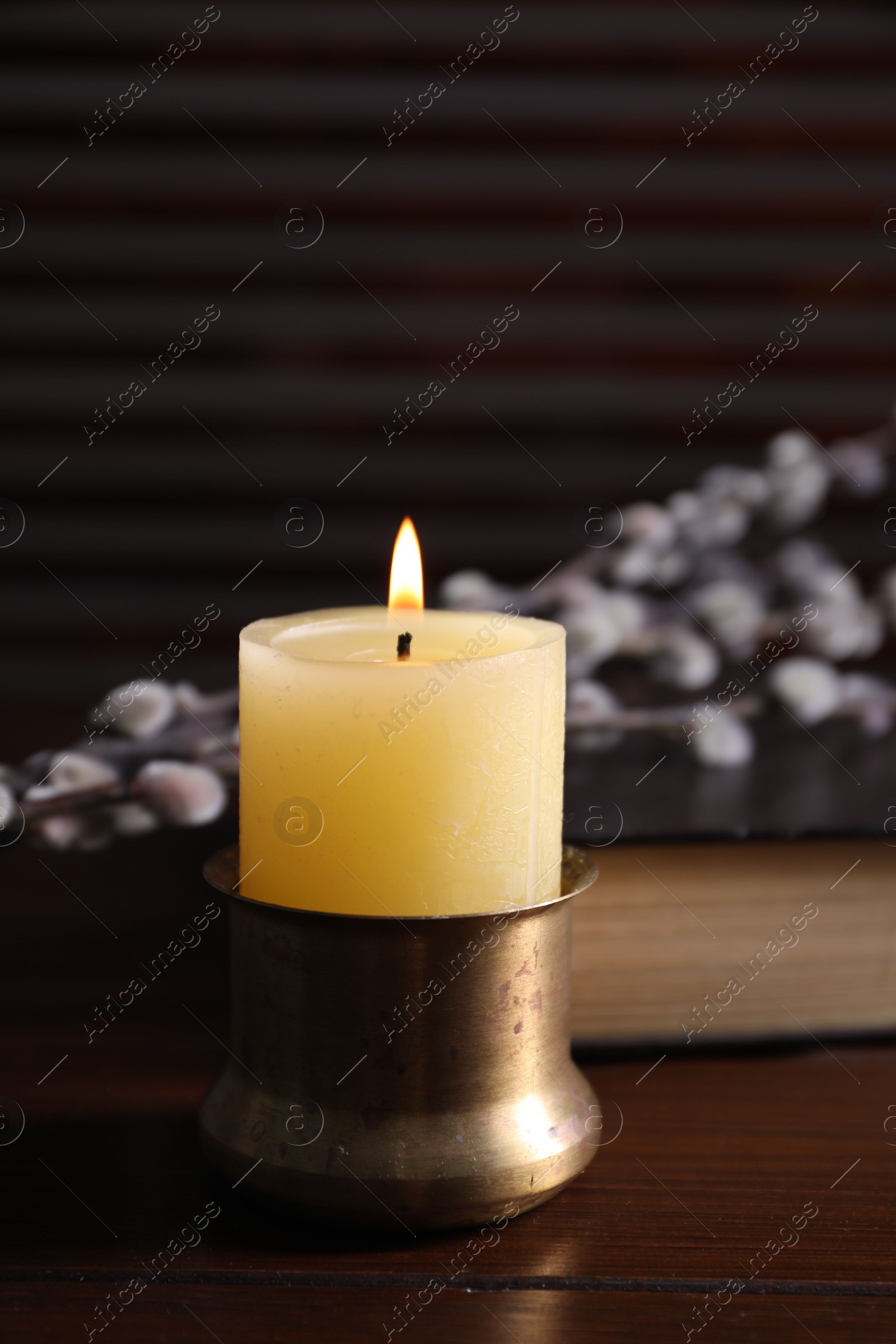 Photo of Burning candle on wooden table, closeup view