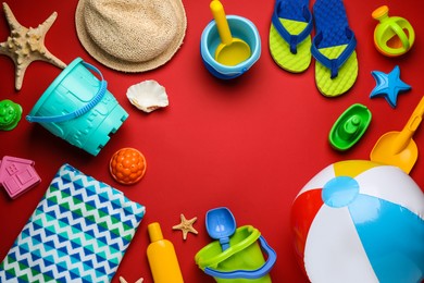 Photo of Frame of beach ball and sand toys on red background, flat lay. Space for text