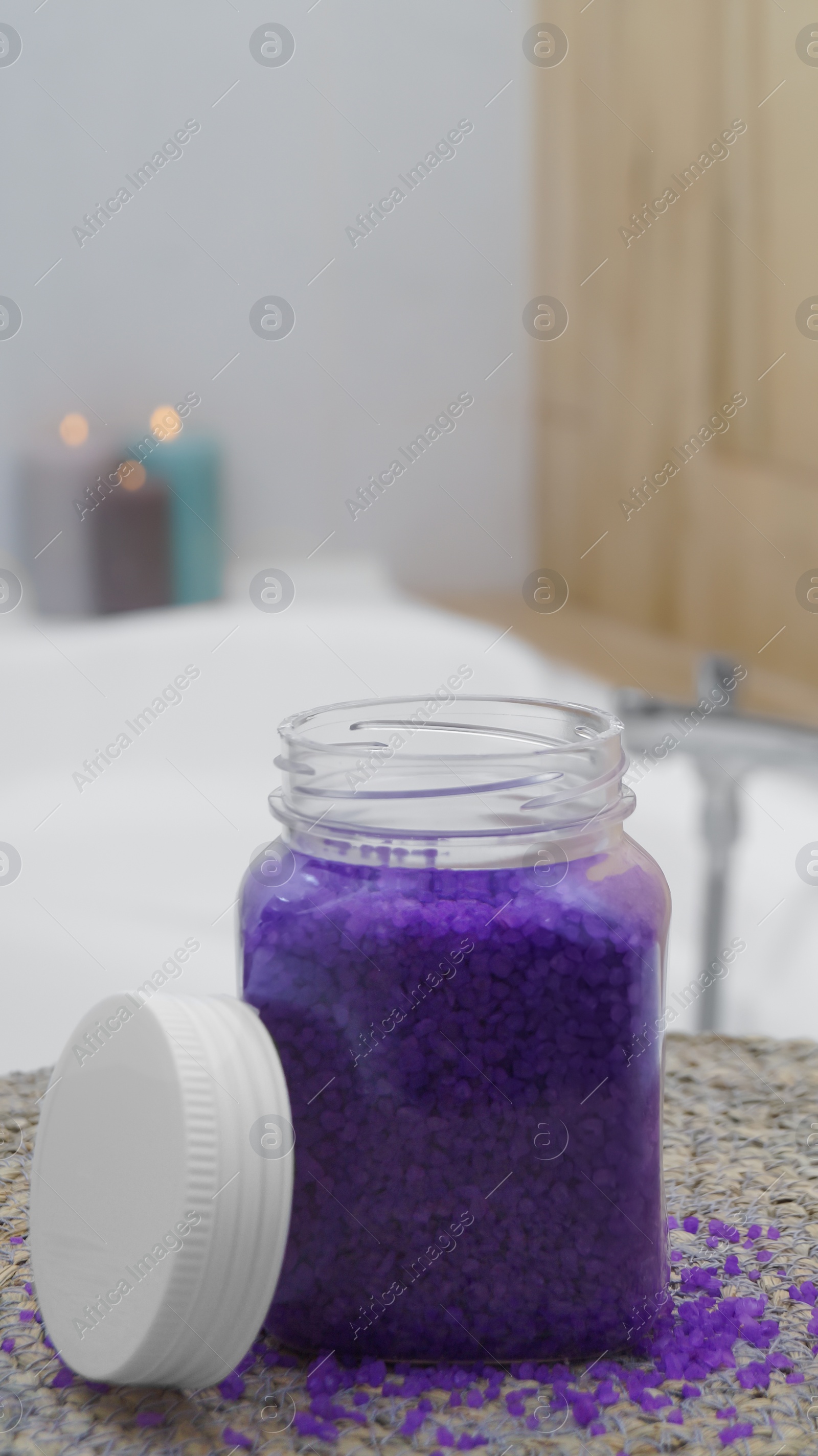 Photo of Jar with bath salt on wicker mat in bathroom