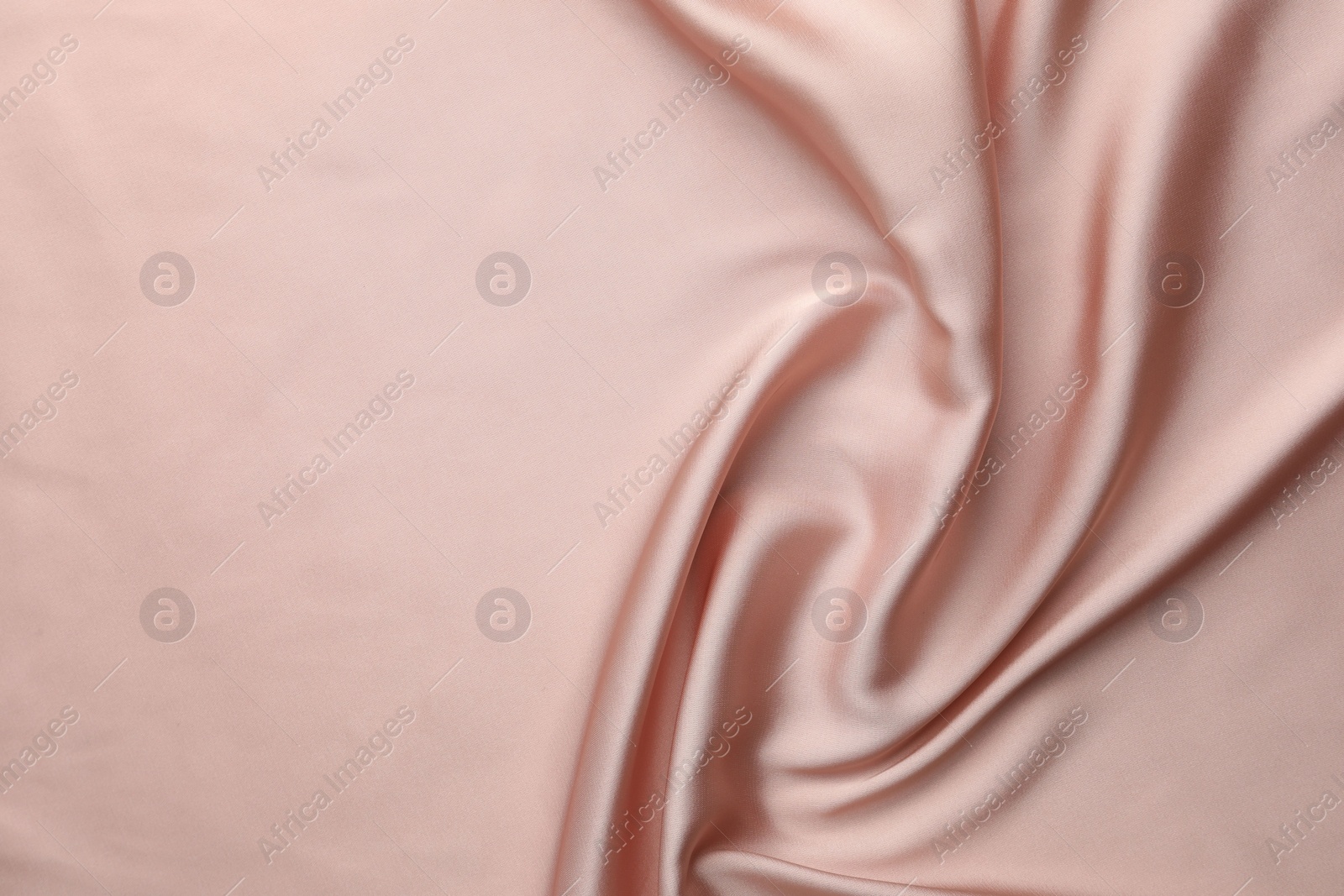 Photo of Crumpled pink silk fabric as background, top view. Space for text