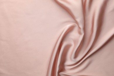 Photo of Crumpled pink silk fabric as background, top view. Space for text