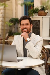 Photo of Man with laptop at table in outdoor cafe