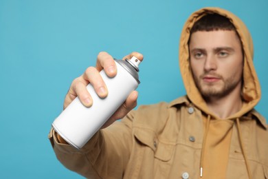 Photo of Handsome man holding white spray paint against light blue background