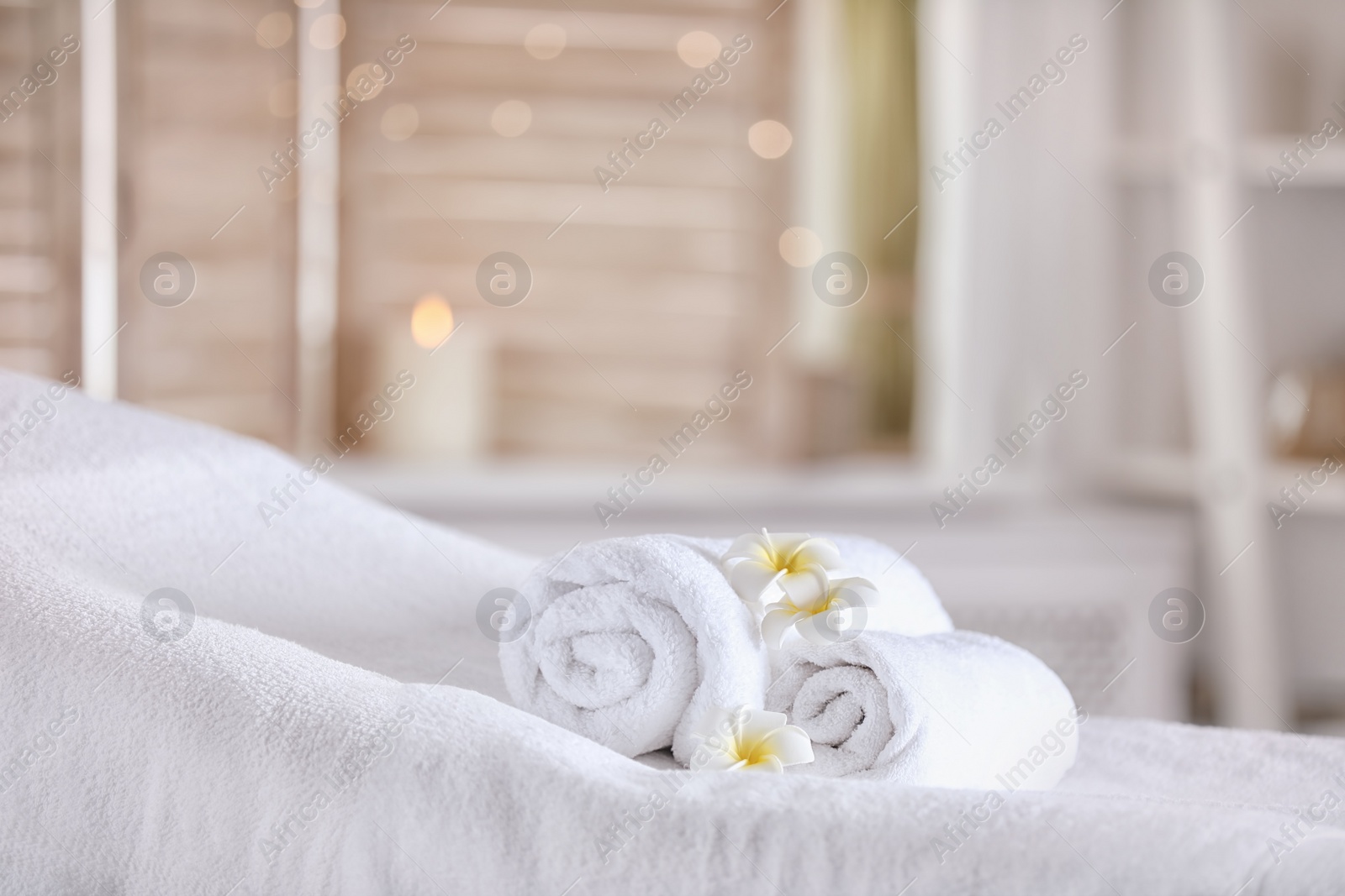 Photo of Towels and candles on massage table in modern spa salon. Place for relaxation