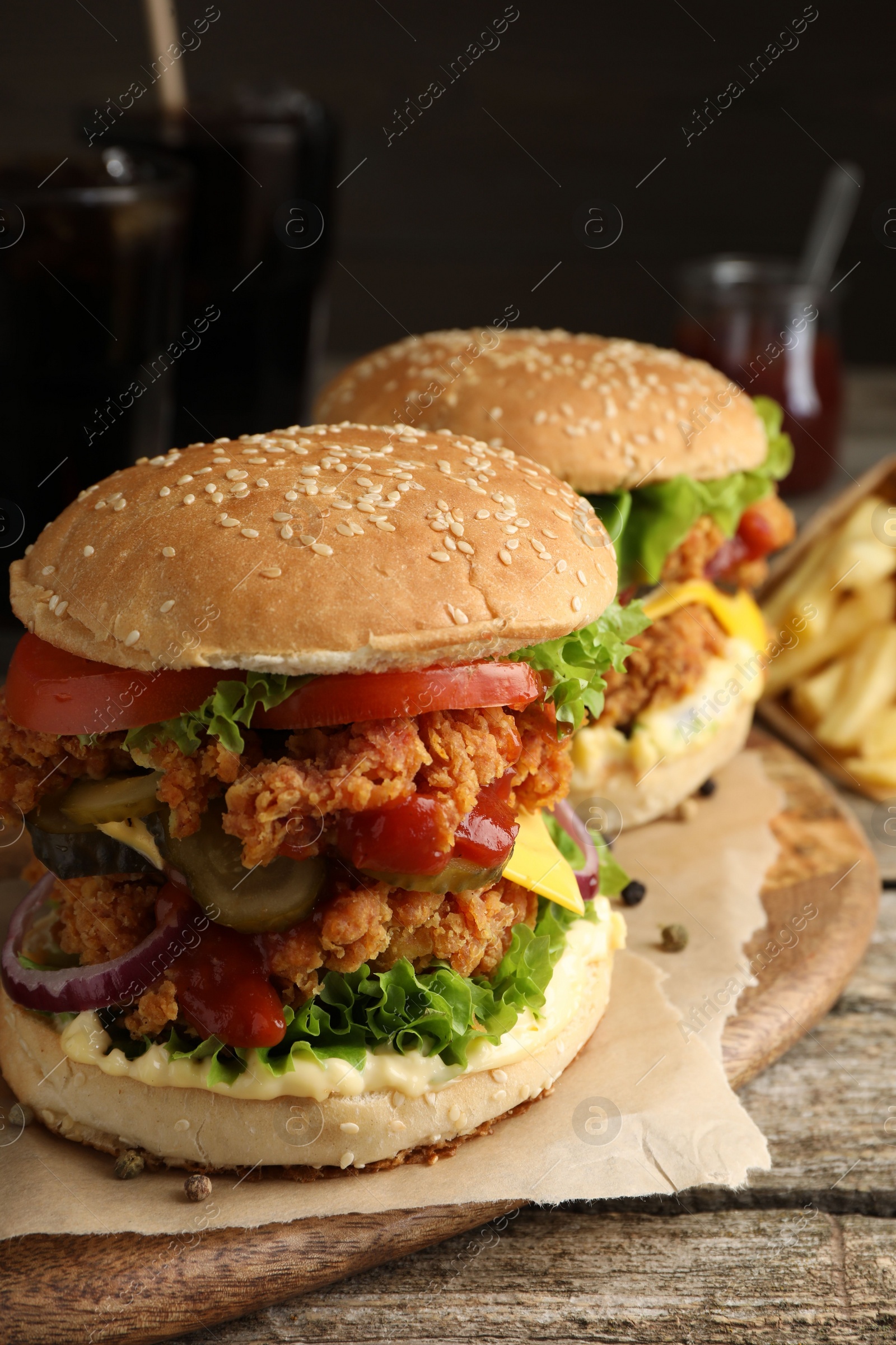 Photo of Delicious burgers with crispy chicken patty on wooden table, closeup