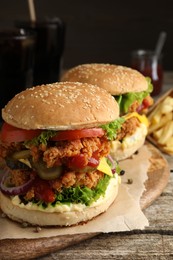 Delicious burgers with crispy chicken patty on wooden table, closeup