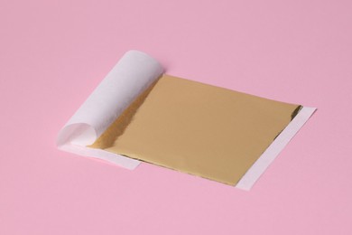 Photo of Edible gold leaf sheet on pink background
