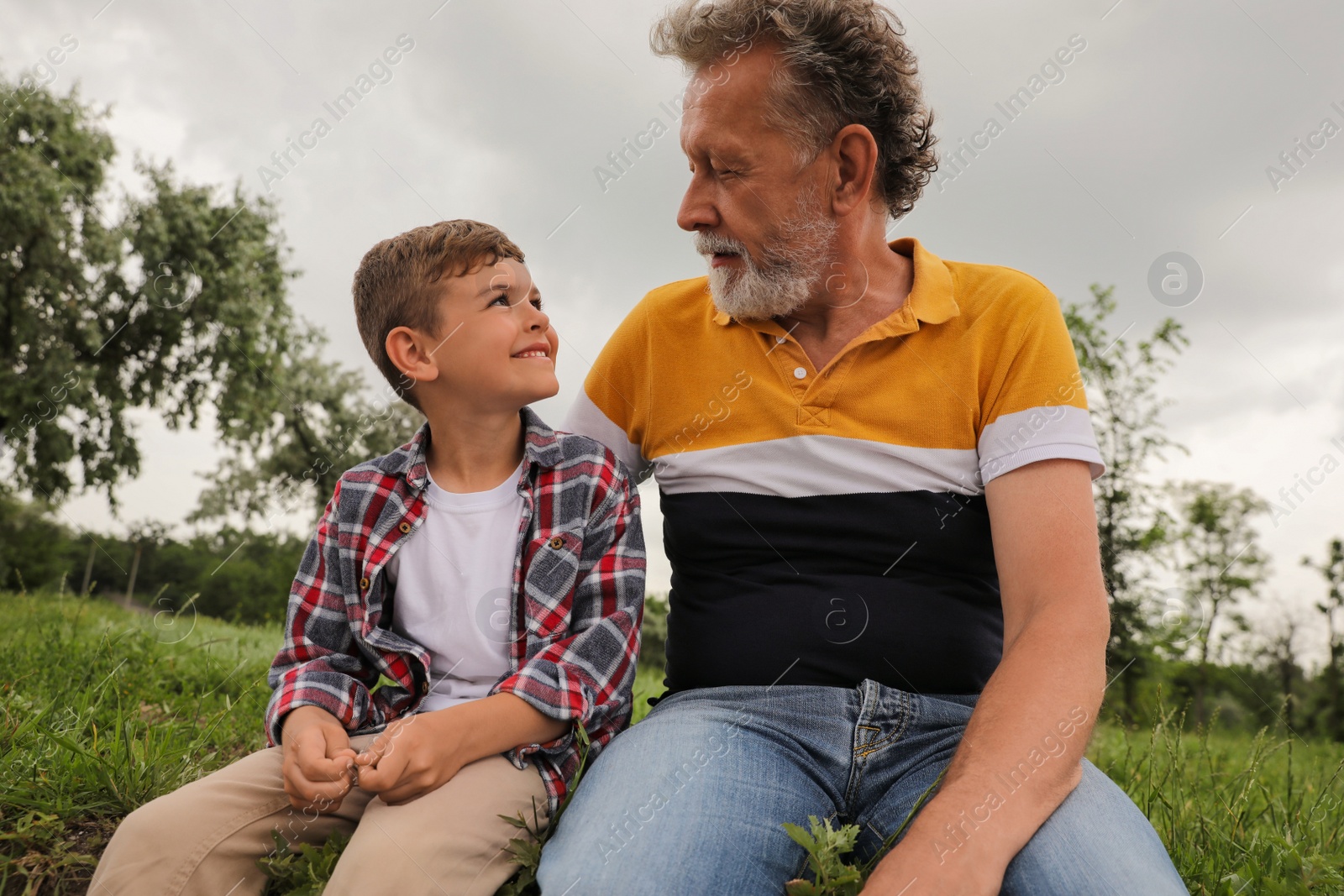 Photo of Cute little boy and grandfather spending time together in park