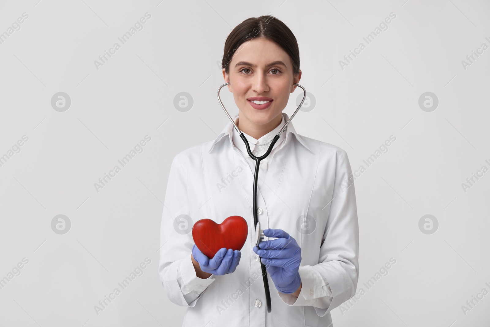Photo of Doctor with stethoscope and red heart on white background. Cardiology concept