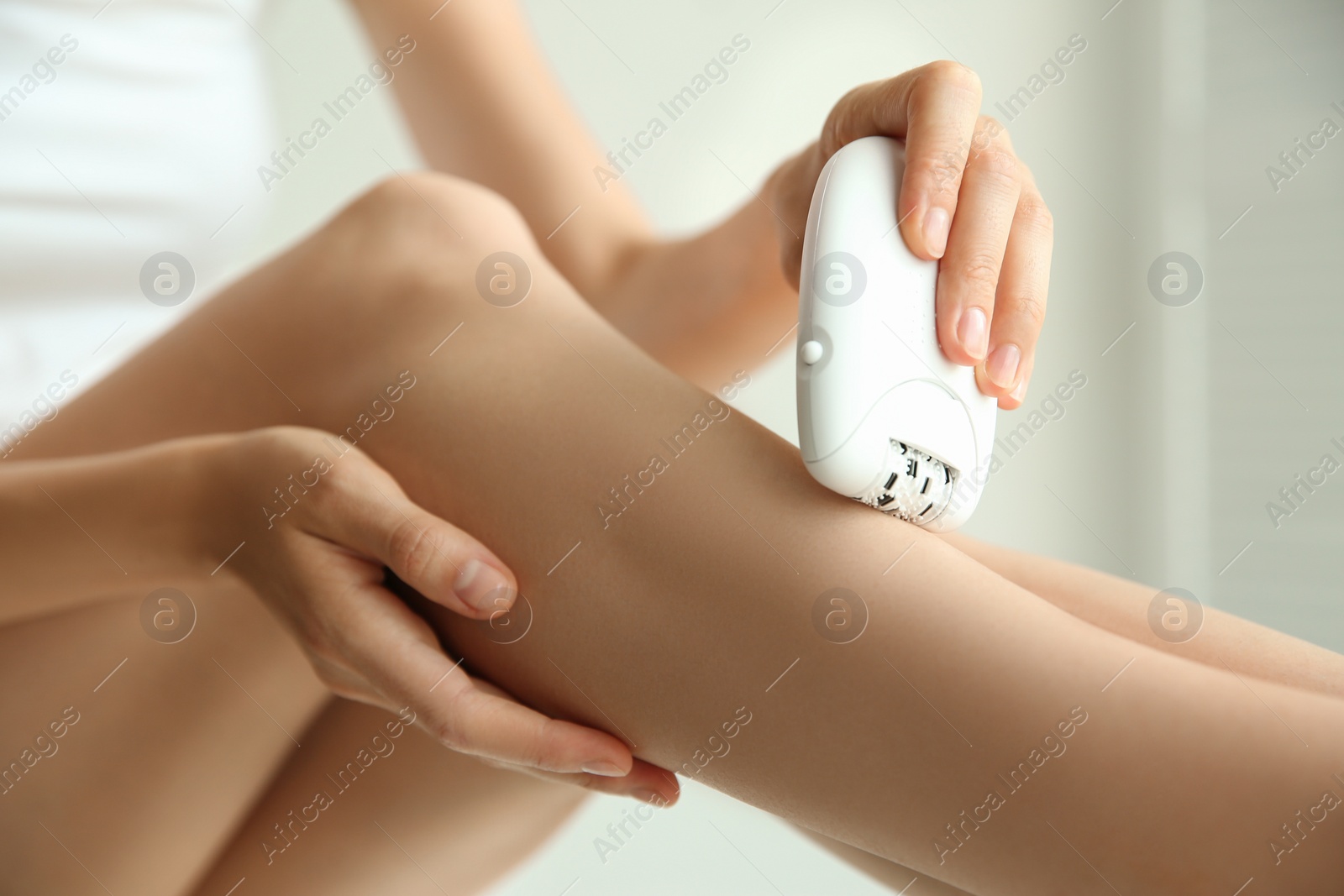 Photo of Woman doing leg epilation procedure on light background, closeup