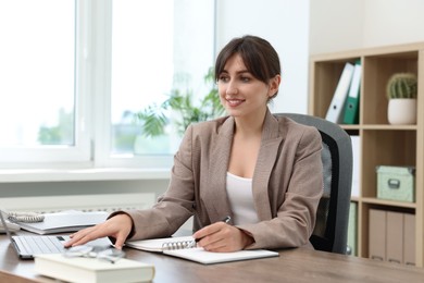 Smiling secretary working at table in office