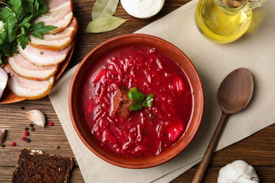 Photo of Stylish brown clay bowl with Ukrainian borsch served on wooden table, flat lay
