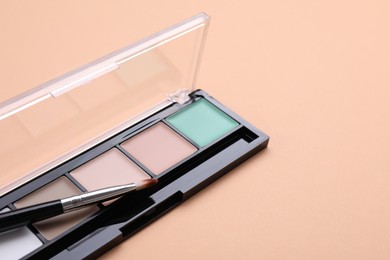 Photo of Colorful contouring palette and brush on beige background, closeup with space for text. Professional cosmetic product