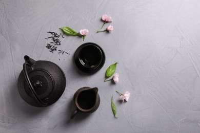 Photo of Beautiful traditional tea ceremony set and sakura flowers on light grey table, flat lay. Space for text