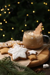 Photo of Decorated cookies on table against blurred Christmas lights, closeup