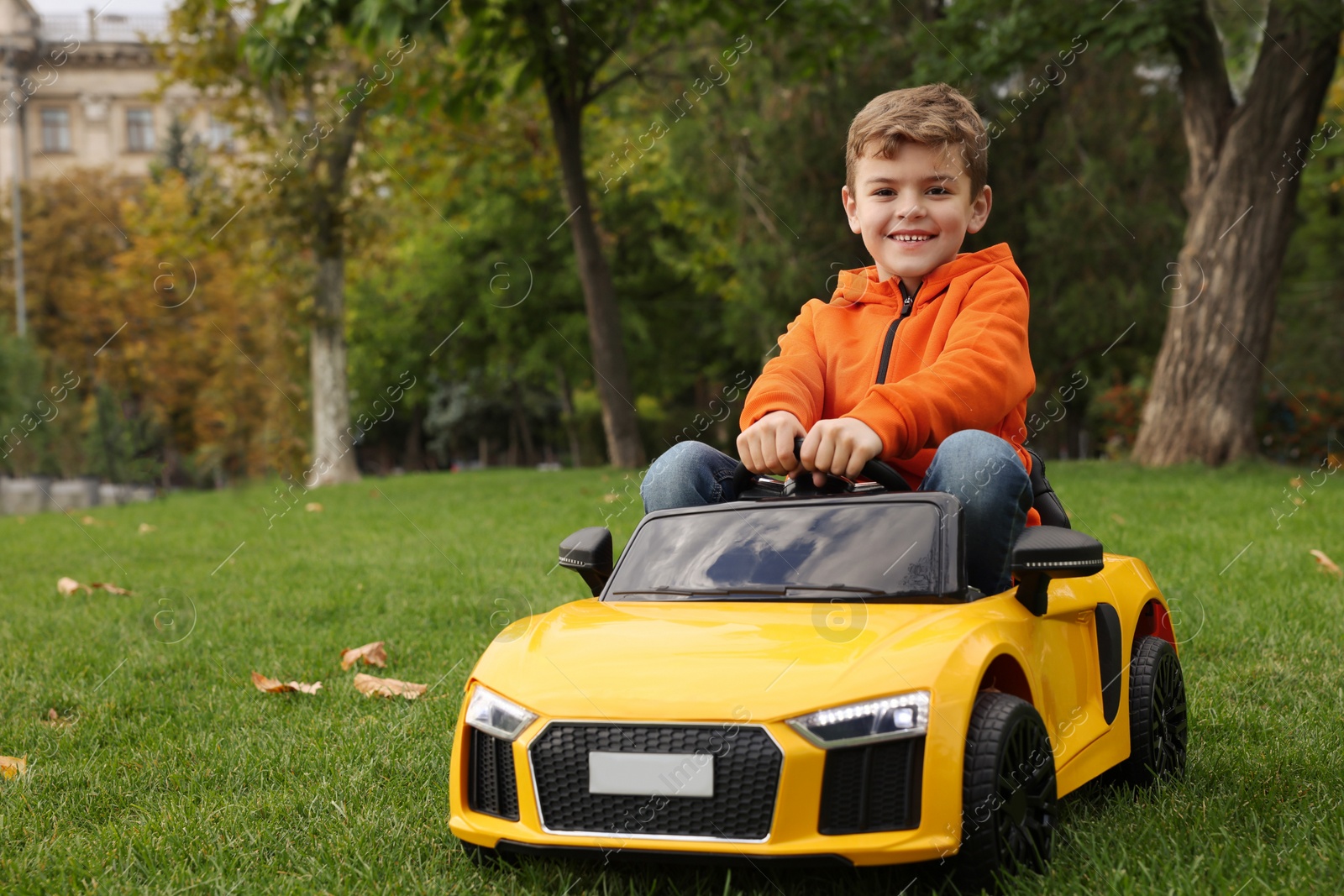 Photo of Cute little boy driving children's car in park. Space for text