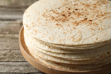 Photo of Stack of tasty homemade tortillas on wooden table, closeup