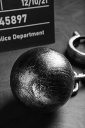 Photo of Metal ball with chain and mugshot letter board on grey table, closeup