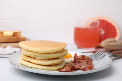 Photo of Plate with tasty pancakes, fried egg and bacon on white table, closeup