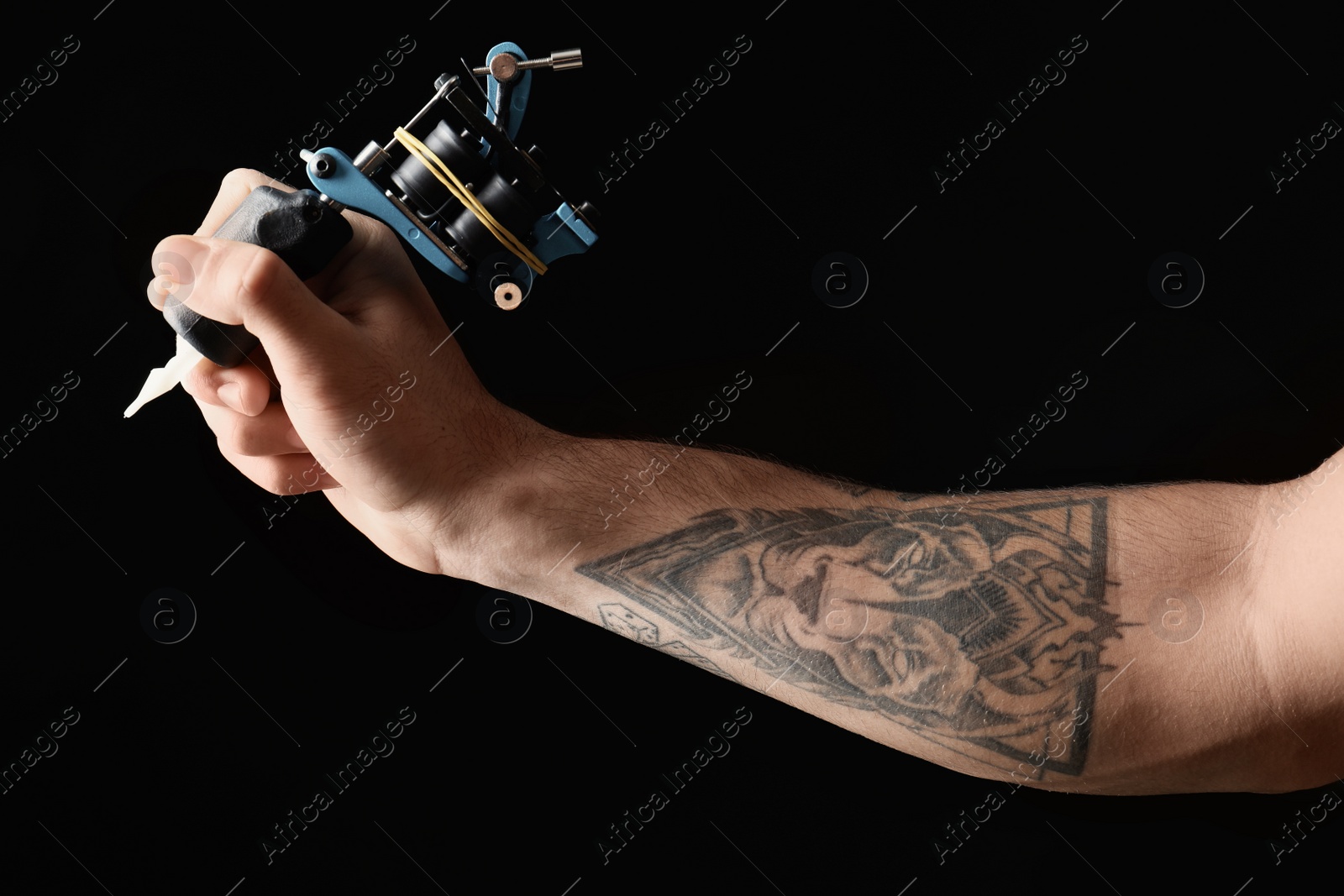 Photo of Professional tattoo artist with machine on black background, closeup