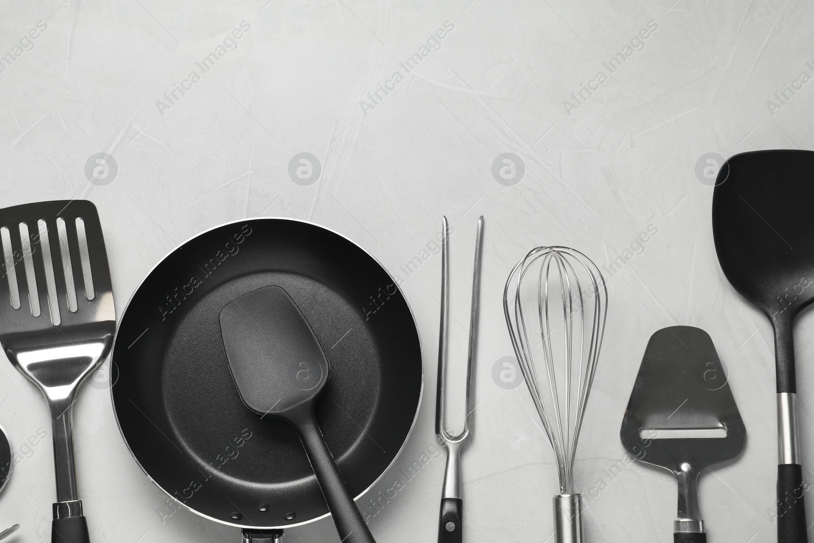 Photo of Different spatulas and other kitchen utensils on grey background, flat lay