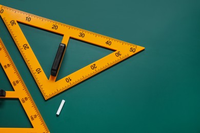 Photo of Triangles and chalk on green chalkboard, flat lay. Space for text