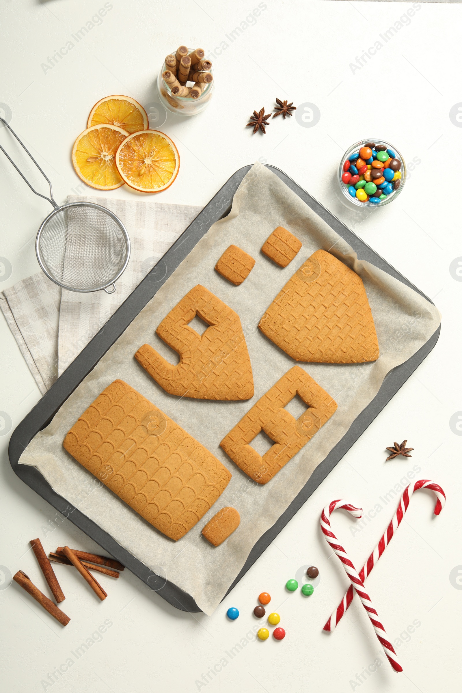 Photo of Parts of gingerbread house and ingredients for decoration on white table, flat lay