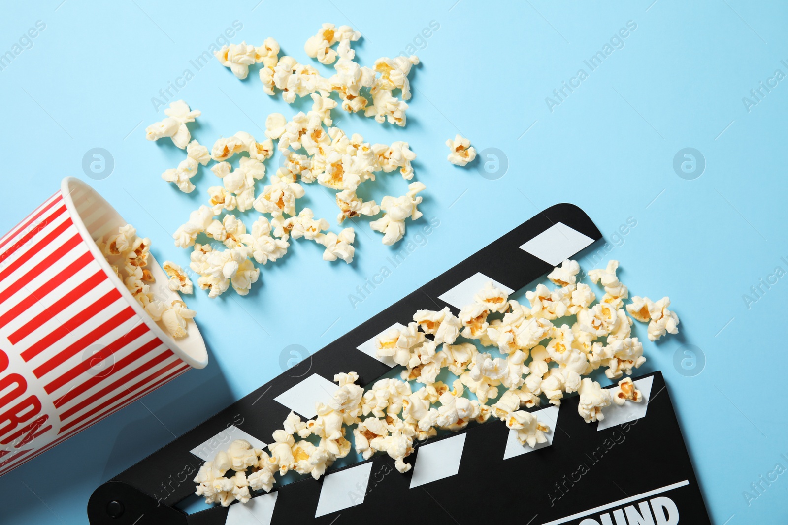 Photo of Popcorn and clapperboard on color background, top view. Cinema snack