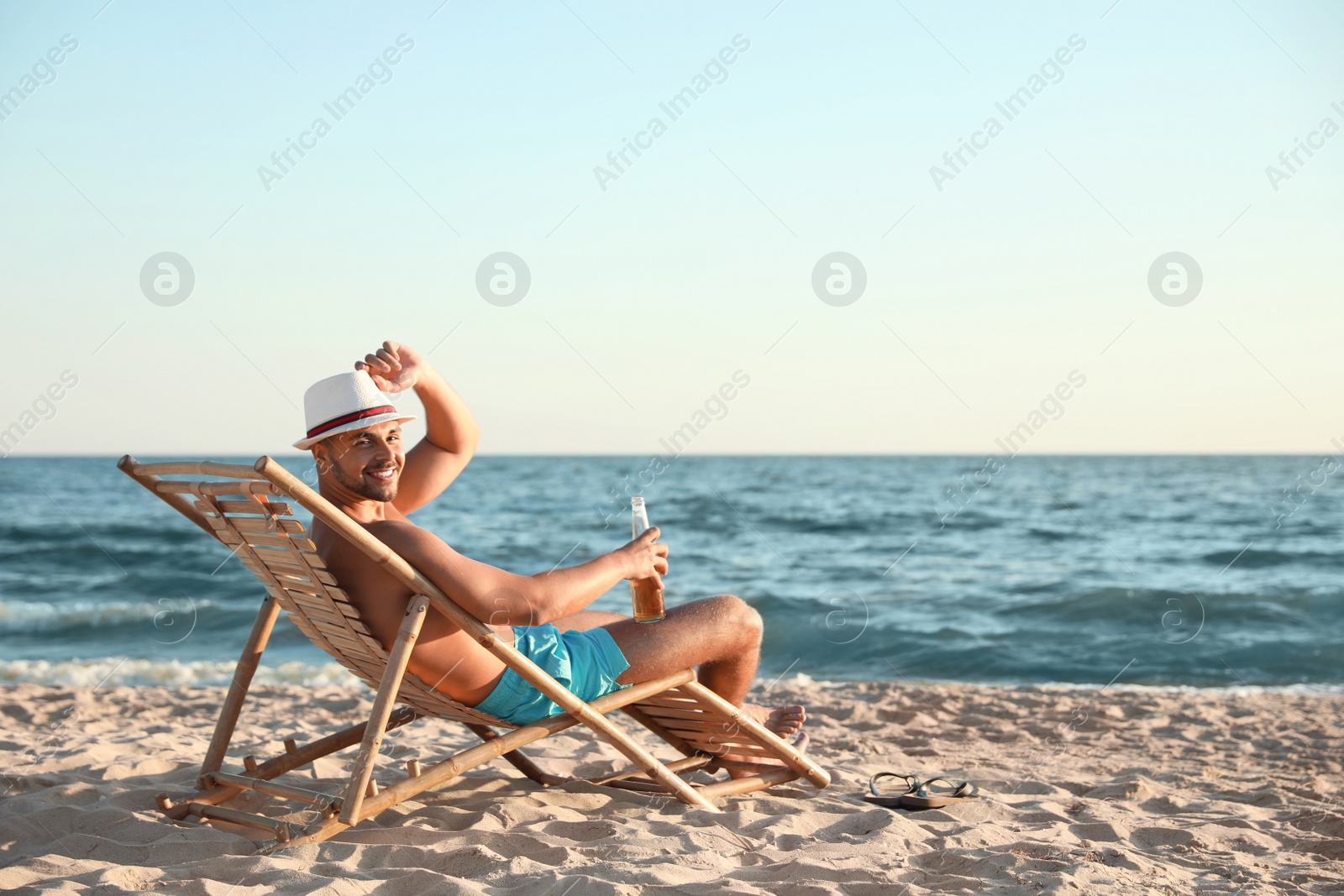 Photo of Young man relaxing in deck chair on beach near sea