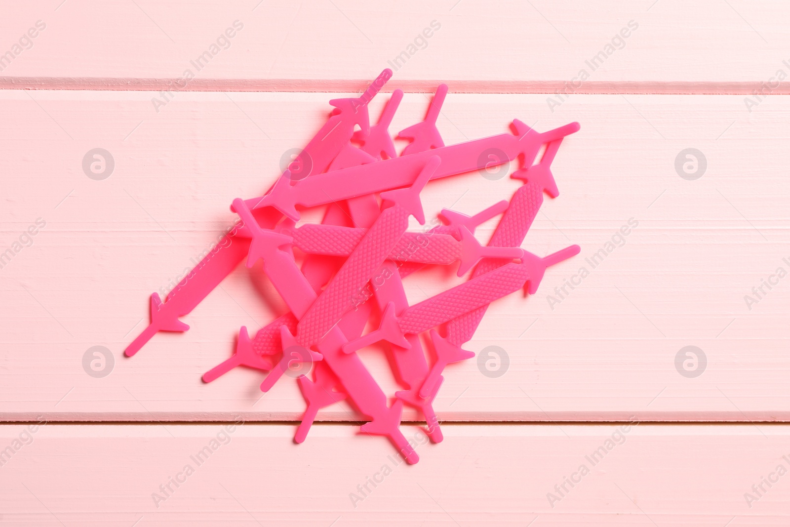 Photo of Silicone shoelaces on pink wooden background, flat lay