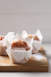 Photo of Delicious muffins with powdered sugar on light table