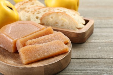 Tasty sweet quince paste, fresh fruits and bread on wooden table, closeup