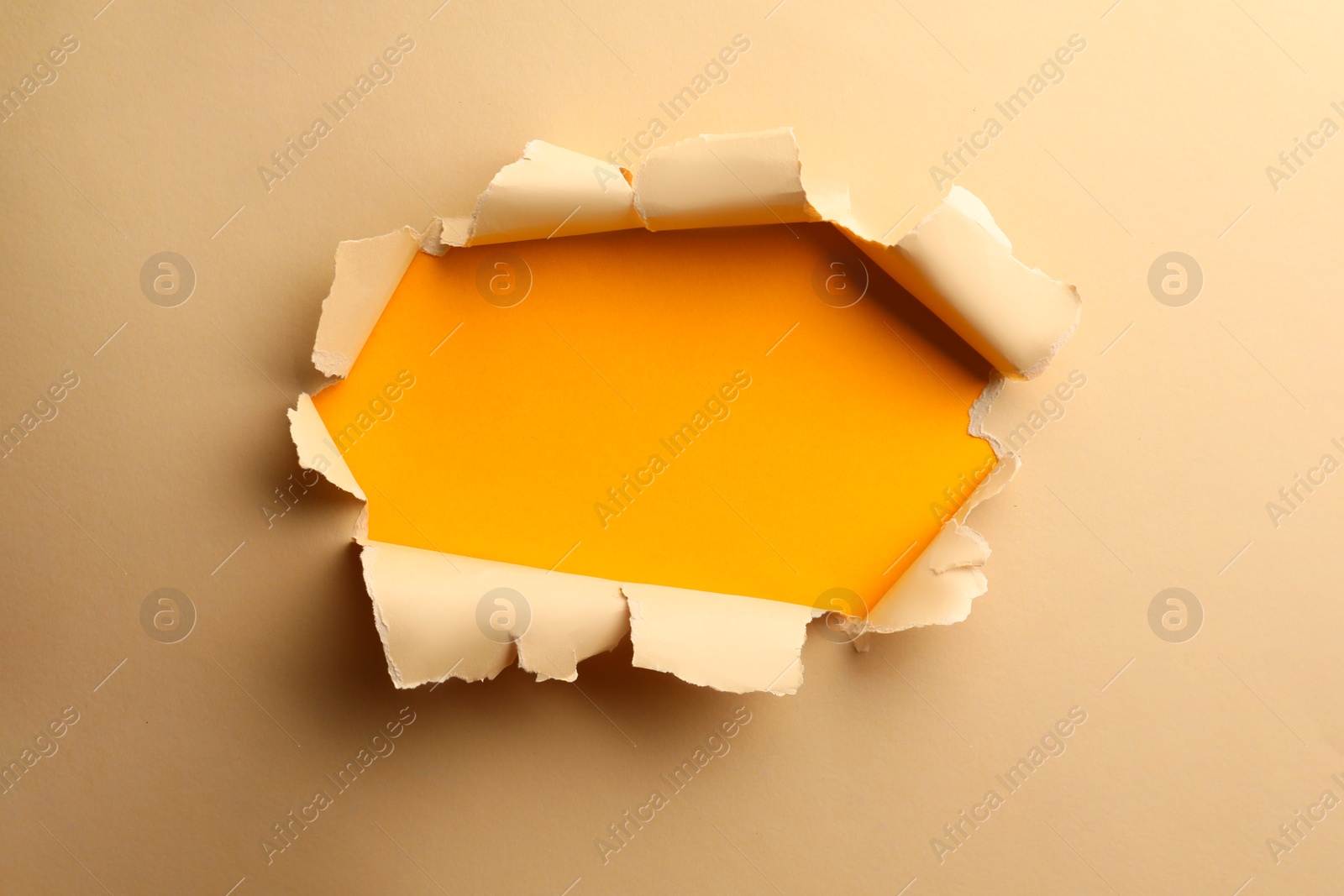Photo of Hole in light beige paper on yellow background
