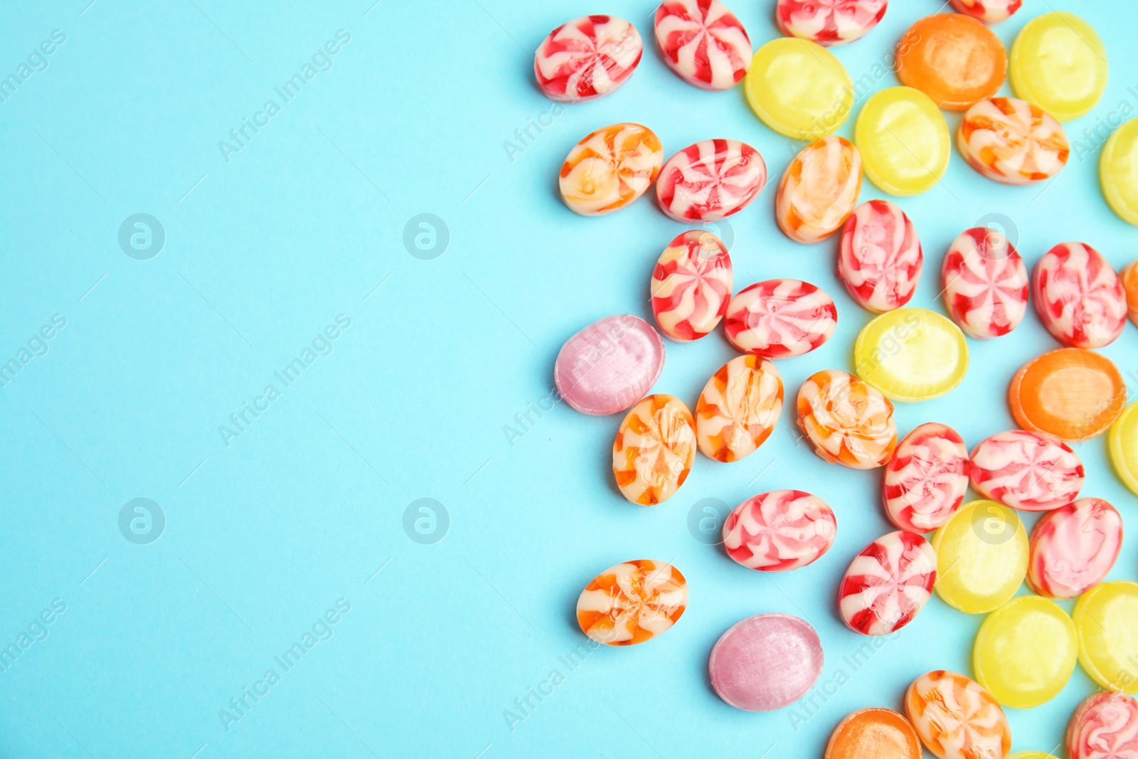 Photo of Flat lay composition with delicious colorful candies and space for text on color background