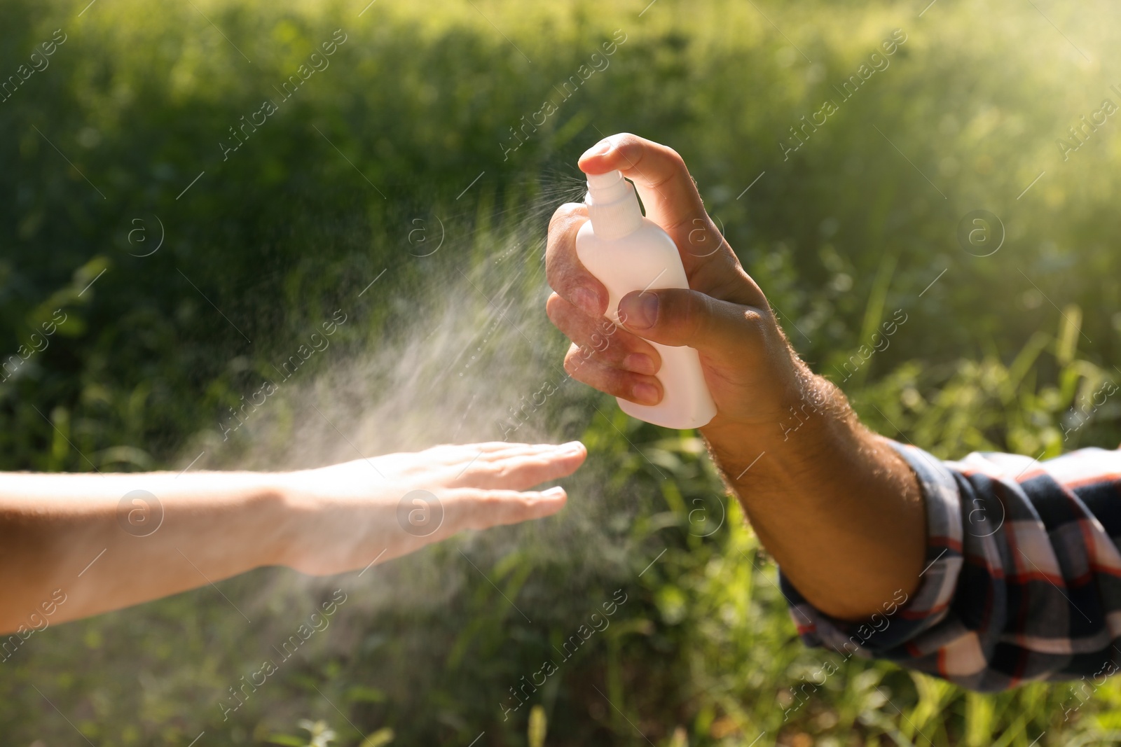 Photo of Father spraying tick repellent on his little child's arm during hike in nature, closeup