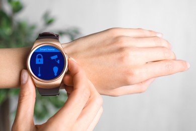 Image of Young woman checking electronic wristwatch with Smart Home Interface indoors, closeup